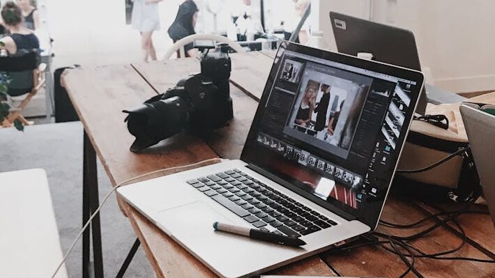 A bright, modern workspace featuring laptops, a camera, and a drawing tablet in an indoor office.